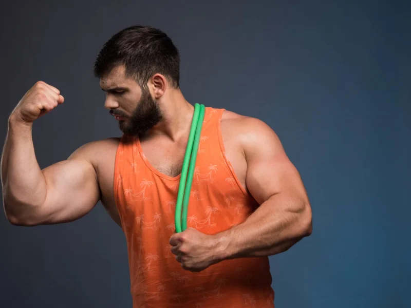 young-man-looking-his-muscles-holding-rubber-sport-2048x1367